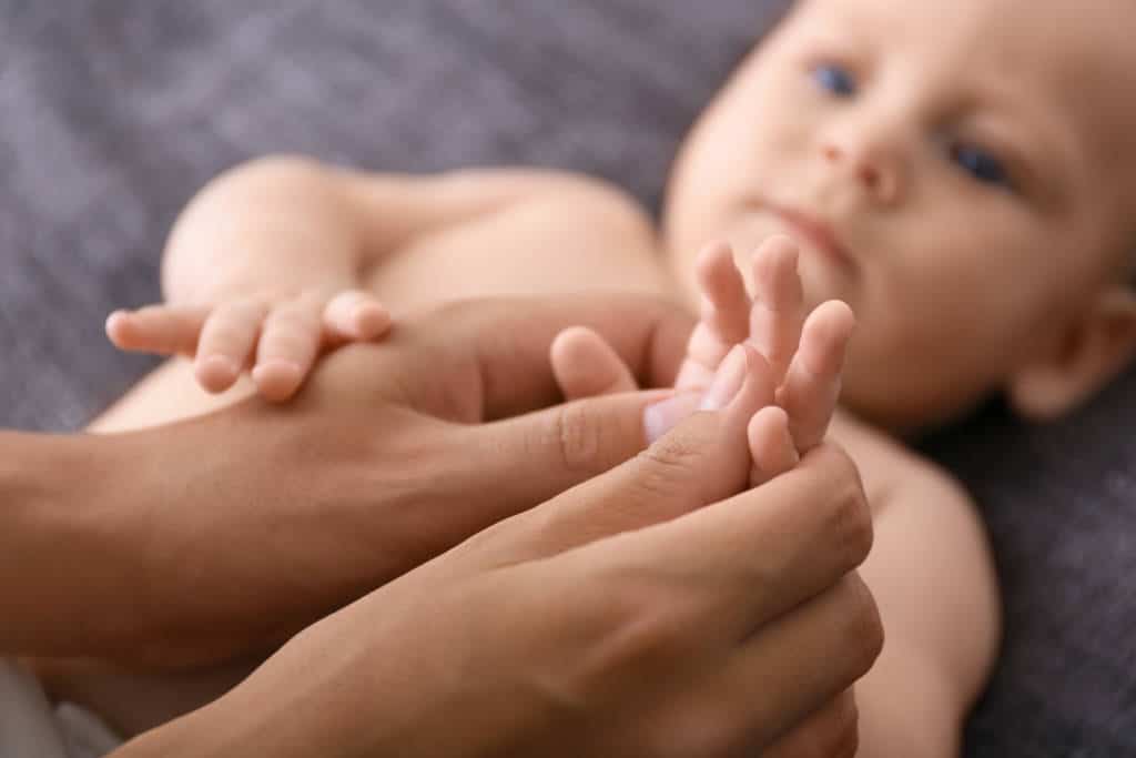 une maman masse la main d'un bébé