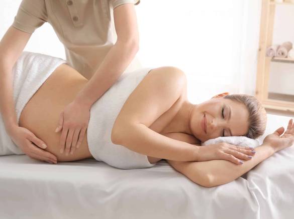 Young beautiful pregnant wfemme enceinte couchée sur le coté reçoit un massage à neuchatel
