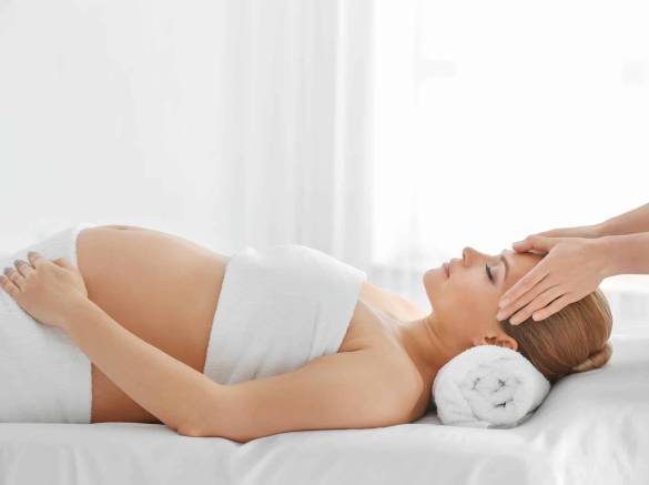 Belle jeune femme enceinte couchée reçoit un massage