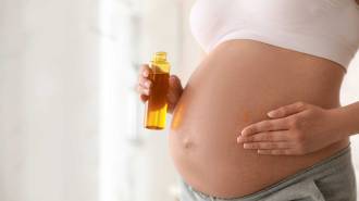 jeune femme enceinte se met de l'huile sur le ventre